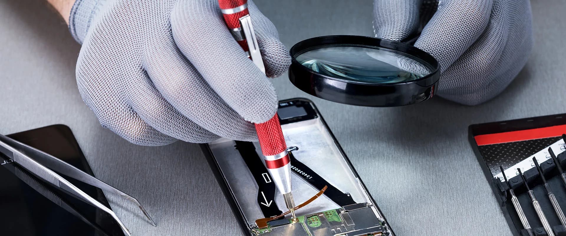 Technician inspecting a phone circuit board through a magnifier